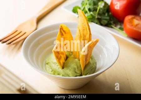 Croustilles de banane au guacamole. Le guacamole est une trempette, une tartinade ou une salade à base d'avocat, développée pour la première fois au Mexique. Banque D'Images