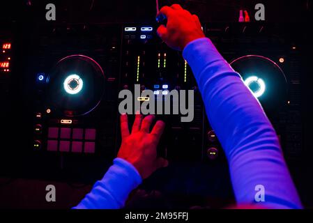 DJ joue de la musique dans un mélangeur professionnel musique à une fête la vue du dessus avec une lumière sombre Banque D'Images