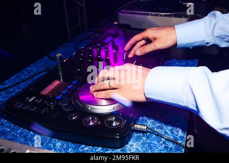 Les mains du DJ en gros plan jouant de la musique sur le mixeur du club Banque D'Images