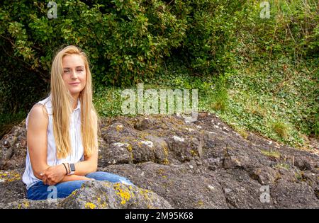 Rhianna Martin, une belle femme blonde, est assise sur des rochers tout en ayant sa photo prise à la plage de Wormit, dans le comté de Fife, en Écosse, au Royaume-Uni Banque D'Images