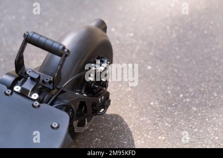 Aile arrière avec roue de scooter électrique sur fond d'asphalte par temps ensoleillé. Banque D'Images