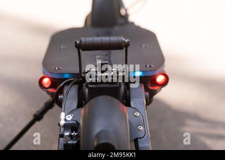 L'arrière du scooter électrique avec un pied repose sur le fond d'asphalte par temps ensoleillé. Banque D'Images