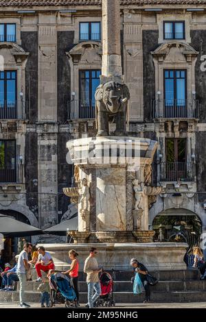 Touristes assis sur les marches de l'obélisque de l'éléphant, symbole de la ville, lors d'une journée d'hiver ensoleillée. Catane, Sicile, Italie, Europe Banque D'Images