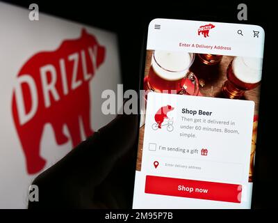 Personne tenant le téléphone portable avec la page Web de la compagnie américaine de livraison d'alcool Drizly LLC sur l'écran devant le logo. Concentrez-vous sur le centre de l'écran du téléphone. Banque D'Images