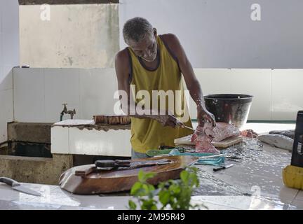 Mahé Seychelles, homme local, nettoyage et filets de poisson à l'intérieur du marché de la ville Banque D'Images