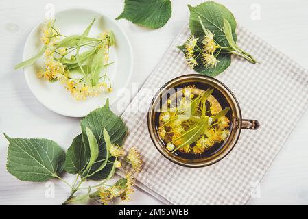 Flat Lay View of Tilia platyphyllos connu comme le thé à base de fleurs de tilleul à grands feuilles, fait à partir d'une fleur fraîchement cueillie avec des feuilles d'arbre et de branche Banque D'Images