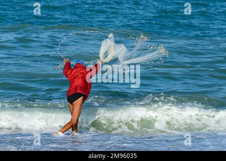 Homme jetant le filet de pêche de la plage à Porto Recanati, Puglia, Italie Banque D'Images