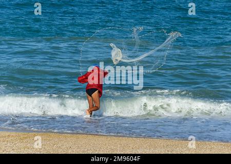 Homme jetant le filet de pêche de la plage à Porto Recanati, Puglia, Italie Banque D'Images