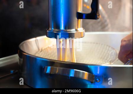 Machine pour préparer des crosses de desserts espagnols sur le marché de Noël nocturne à Bilbao, en Espagne Banque D'Images