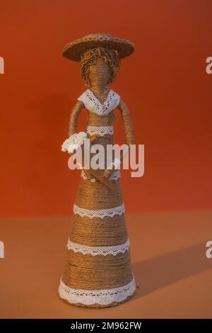 Figure décorative en paille en forme de femme avec fleurs. Poupée fille en chapeau avec fleurs en fils. BRICOLAGE Banque D'Images