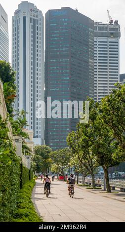 Deux femmes cyclistes à vélo le long de la rivière Singapore à Boat Quay Singapore Banque D'Images