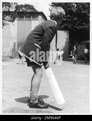 Les écoliers jouent à un jeu de cricket impromptu ; un garçon se prépare à battre