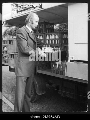 Un inspecteur du gouvernement britannique vérifie la qualité des bouteilles de lait sur des caisses à l'arrière d'un laitat. Banque D'Images