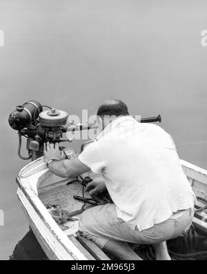 Un homme d'âge moyen balding et en surpoids tente de réparer son moteur de bateau à moteur ! Banque D'Images