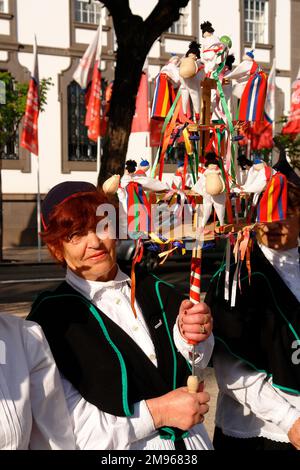 Une femme d'un groupe folklorique du village de Camacha, vu ici à Funchal, la capitale de Madère. Elle tient un instrument de musique connu sous le nom de brinquinho, un bâton décoré de poupées en bois, de cloches et de castanets, qui est secoué vers le haut et vers le bas pour que le groupe danse autour. Banque D'Images