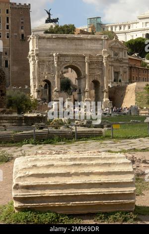 Vue sur l'Arche de Septimius Severus à Rome, Italie. Il s'agit d'une arche triomphale en marbre blanc dans le Forum romain, dédiée en 203 à la commémoration des victoires parthiennes de l'empereur Septimius Severus et de ses deux fils, Caracalla et Geta, dans les deux campagnes contre les Parthiens. Au premier plan se trouve une section d'une colonne cannelée. Banque D'Images