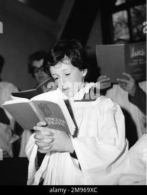 Un choirboy chantant dans un chœur d'église à l'église Salfords Church, Horley, Surrey. Il tient un livre intitulé 'louange anglais', bien que d'autres accords utilisent 'le Livre rouge de Carol'. Banque D'Images