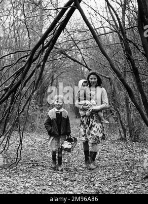 Une mère tzigane et deux filles, membres de la famille Vincent, marchant dans un bois dans la région de Newdigate à Charlwood, Surrey, avec un jeune homme à l'arrière-plan. Banque D'Images