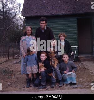 Une famille gitane itinérante, deux adultes et cinq enfants, posant avec leurs deux chiens de compagnie à l'extérieur du bungalow où ils ont été relocagés, à Beare Green, Surrey. Banque D'Images