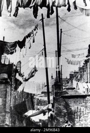 De nombreuses lignes de lavage avec des vêtements accrochés à sécher à l'arrière d'un logement en terrasse dans une zone minière non identifiée du sud du pays de Galles. Banque D'Images