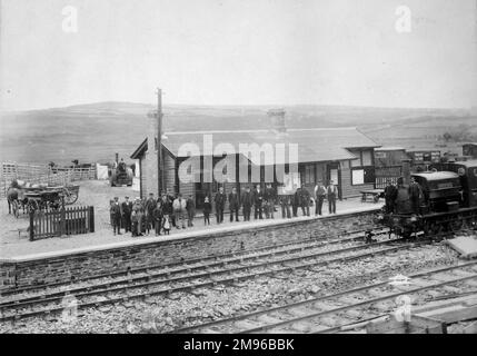 Une longue file de passagers et de personnel attendant sur la plate-forme à la gare de Goodwick sur le chemin de fer Great Western, Pembrokeshire, Dyfed, au sud du pays de Galles. Ils regardent tous la caméra. Deux cheminots se trouvent à l'avant d'une locomotive appelée Ringing Rock sur la droite. La station a ouvert ses portes en 1899. En 1904, elle a été rebaptisée Fishguard & Goodwick. Elle a fermé ses portes en 1964, mais a rouvert ses portes en 2012 après une longue campagne d'un groupe de passagers. Banque D'Images