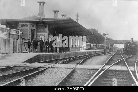 Vue sur la gare de Clynderwen (ou Clunderwen) à Pembrokeshire, dans le sud du pays de Galles, sur le Great Western Railway. Sept hommes et un garçon se tiennent en ligne sur la plate-forme, y compris probablement le maître de la gare, le collecteur de billets et les porteurs. Quatre hommes sur la ligne à la distance près du pont testent la voie. Banque D'Images