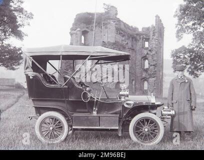 Un homme de campagne âgé avec une voiture très ancienne (toit en place) devant les ruines du château de Crickhowell, Crickhowell, Powys, Mid Wales. Banque D'Images