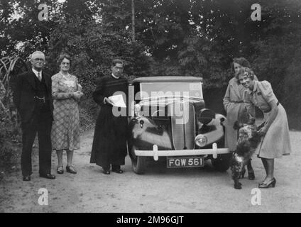 Un groupe de cinq personnes avec un chien de spaniel et une voiture. Banque D'Images