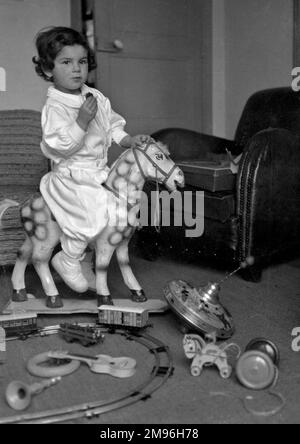 Un petit garçon jouant avec ses jouets et de l'équitation d'un cheval de passe-temps. Banque D'Images