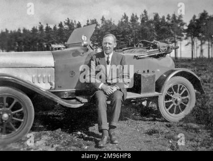 Un homme assis sur la planche à pied d'une voiture de sport. Banque D'Images