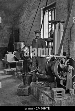 Workman dans une usine utilisant des machines. L'usine a produit des éclats de plomb pour l'utilisation dans des obus d'artillerie à haut risque en WW1. Banque D'Images