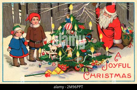Père Noël se cache derrière un arbre de Noël magnifiquement décoré, qui est chargé de cadeaux pour les deux petits enfants qui ont évidemment été très bons cette année. Banque D'Images