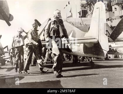 Les pilotes marchent devant un Grumman F6F Hellcat sur un pont porteur. Banque D'Images