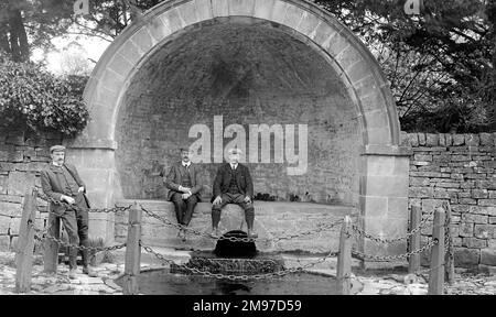 Trois hommes à Hall Well, Tissington, qui profitent d'une pause après leur visite. C'est la scène de certains des célèbres 'Well dressing' dans le Derbyshire. Banque D'Images