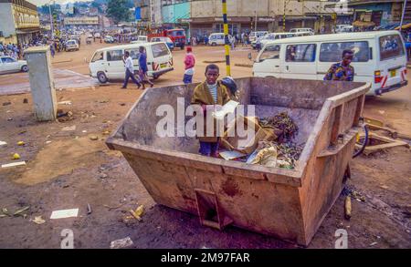 Ouganda, Kampala, enfant de la rue à la recherche de nourriture dans un conteneur de déchets. Banque D'Images