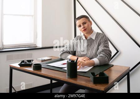 une femme agent d'assurance remplit les documents tout en étant assise à une table dans le bureau Banque D'Images