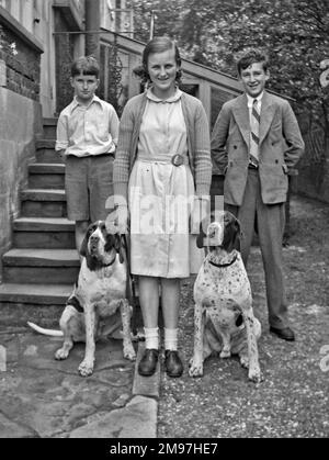 Trois enfants et deux chiens dans un jardin. Banque D'Images