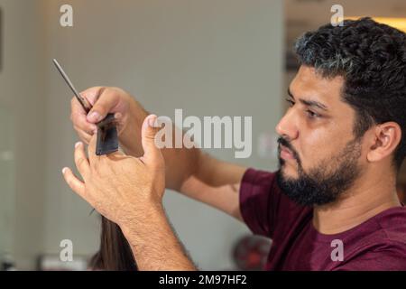 Goiania, Goiás, Brésil – 10 janvier 2023: Détail d'un coiffeur séparant une serrure de cheveux d'un client à couper. Banque D'Images