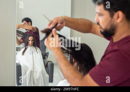 Goiania, Goiás, Brésil – 10 janvier 2023: Détail d'un coiffeur séparant une serrure de cheveux d'un client à couper. Banque D'Images