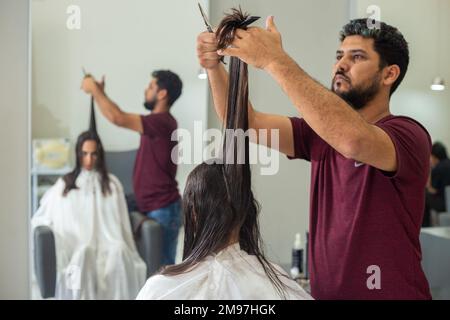 Goiania, Goiás, Brésil – 10 janvier 2023: Détail d'un coiffeur séparant une serrure de cheveux d'un client à couper. Banque D'Images