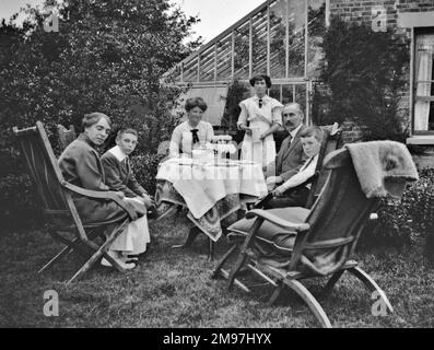 Groupe familial de six personnes prenant un thé dans un jardin. Banque D'Images