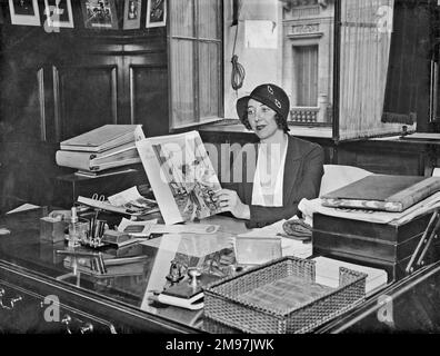 Femme à la mode assise à un bureau dans un bureau. Banque D'Images