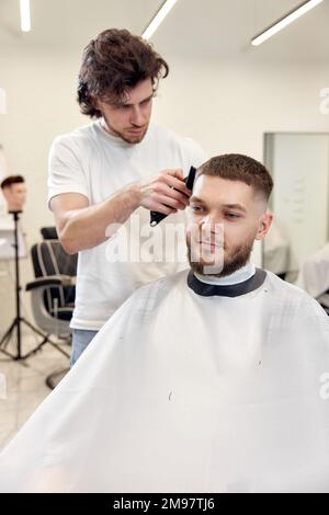 Barbiche tondre les cheveux avec une tondeuse sur un homme barbu Banque D'Images