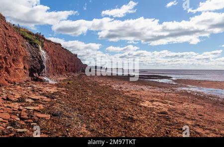 Eau qui coule sur le bord d'une falaise sur la plage d'argile rouge, Île-du-Prince-Édouard, Canada Banque D'Images