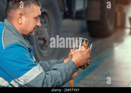 Le mécanicien d'automobiles répare le chariot. Réparation et diagnostic professionnels des tracteurs et équipements cargo. Le mécanicien en atelier considère les pièces de rechange. Banque D'Images