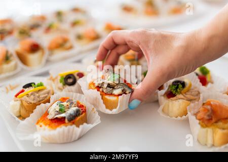 Gros plan de la main femelle tenant le canape. Concept de repas sous forme de buffet. Banque D'Images