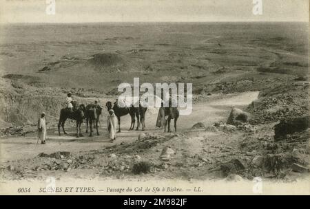 Les nomades se tiennent avec leurs chameaux en traversant le passage 'Col de SFA' dans les déserts de Biskra, en Algérie. Biskra était une ville de garnison française, connue pour son oasis saharienne. Banque D'Images