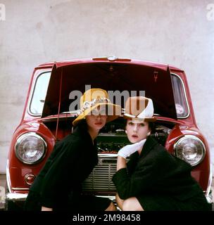 Tatler Cover photoshoot se concentrant sur les chapeaux et le Motor Show -- deux modèles féminins posant devant une mini voiture rouge. Une variante de ce photoshoot particulier a été utilisée pour la couverture du numéro de Tatler du 21 octobre 1959 (voir image 11064837). Banque D'Images