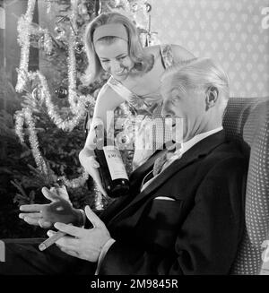 Publicité pour EMU sherry -- modèles masculins et féminins posant dans la scène de fête de Noël. Banque D'Images