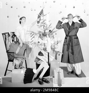 Modèles masculins et féminins dans une scène du matin de Noël avec arbre et cadeaux. Banque D'Images